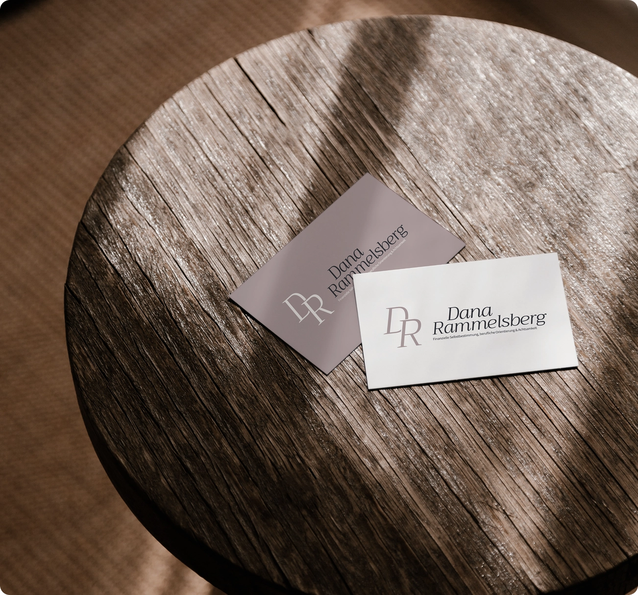 beige-weiße Visitenkarten für Coaching-Unternehmen auf Holztisch liegend
