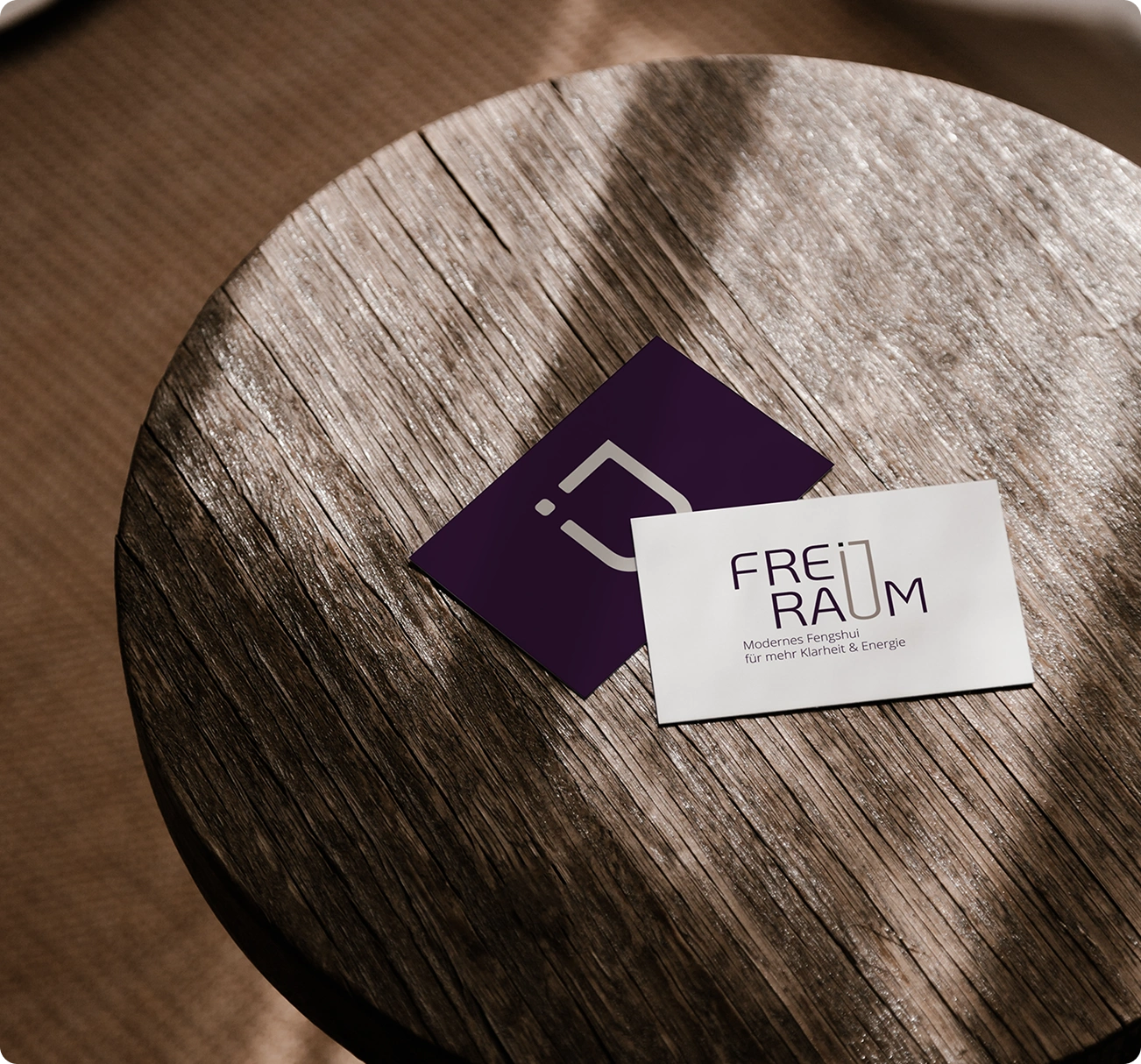 Lila-weiße Visitenkarten für Feng Shui Beratung auf Holztisch liegend