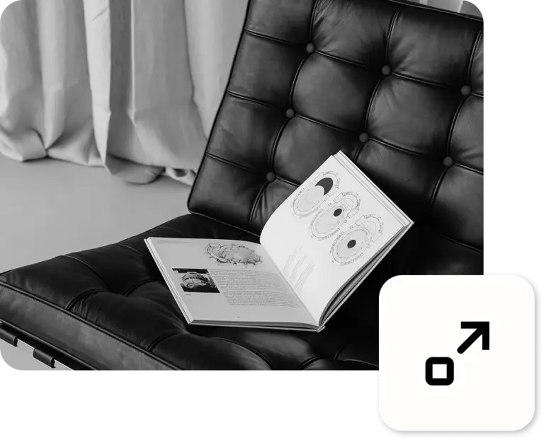 Ein aufgeklapptes Buch zum Thema Design auf einem schwarzen Ledersessel liegend