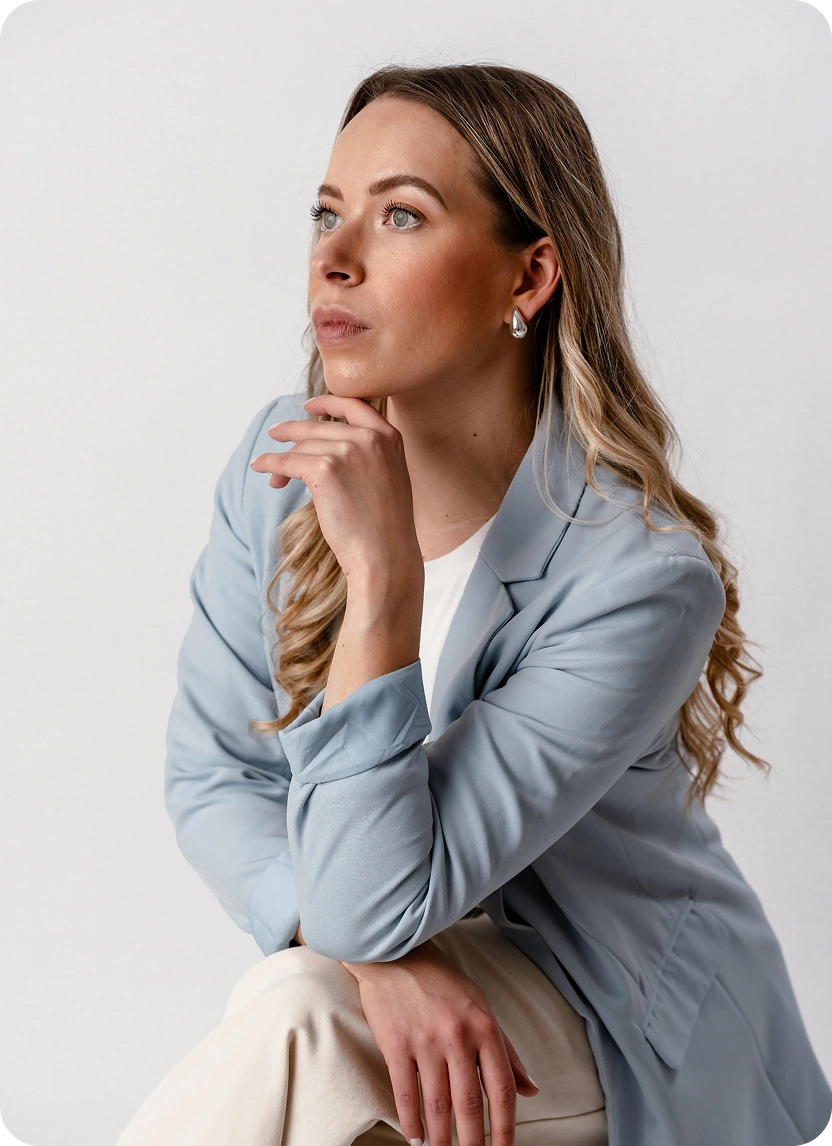 Geschäftsführerin Anna Menzen mit Hand am Kinn und blauem Blazer zur Seite blickend