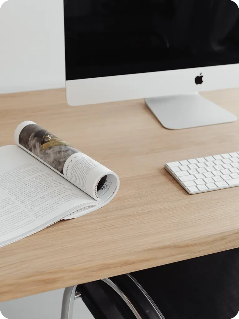 Arbeitsplatz mit Zeitschrift, Bildschirm und Tastatur auf einem Holztisch